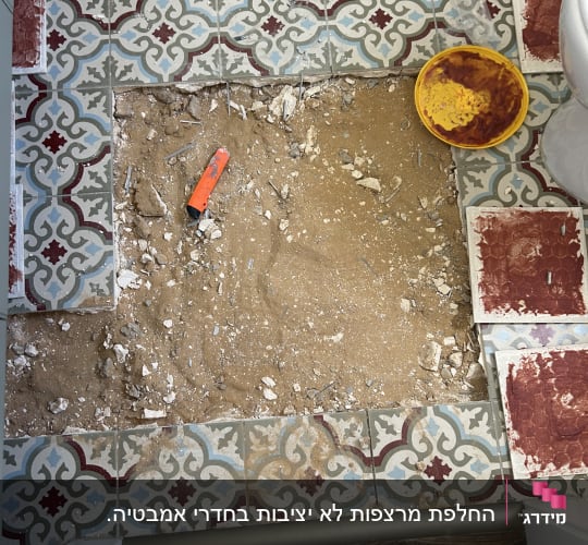 רצפה עם אריחים שבורים וכלי עבודה כתום
